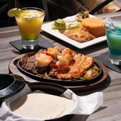 Mixed chicken, beef and shrimp fajita plate accompanied with house cocktails.
