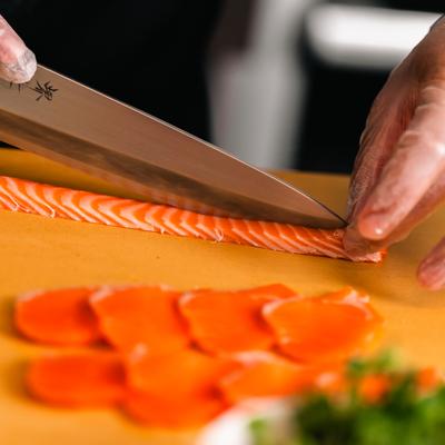 Chef slicing salmon on a cutting board.