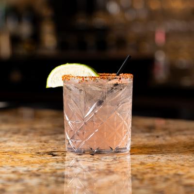 Grapefruit Paloma glass resting on bar counter.