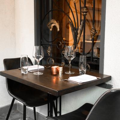 A table for two by a wrought iron window, set with glasses, napkins and cutlery