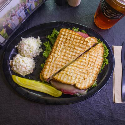 Sweet Bologna Sandwich served with two scoops of coleslaw and a pickle.