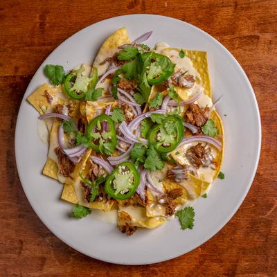 Brisket nachos topped with melted cheese, cilantro, red onions, and jalapenos.