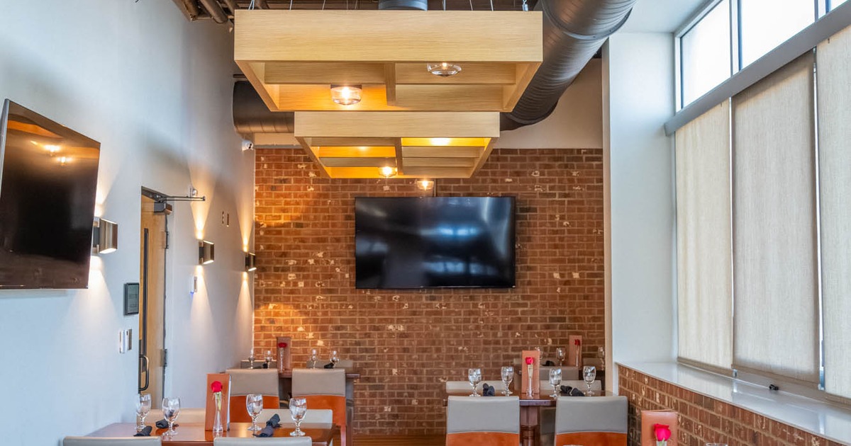 A dining area with set tables, brick walls and TVs