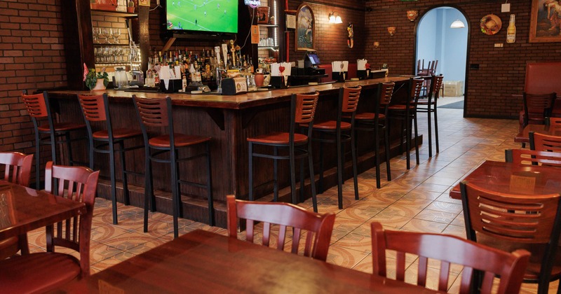 Restaurant interior with a wooden bar, TV showing soccer and colorful ceiling banners