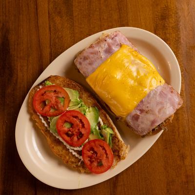 Ham and cheese sandwich with avocado and tomato slices.