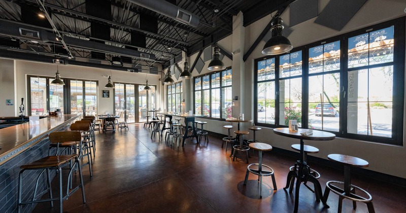 Interior, bar stools and tables, large window on the right, large glass door entrance in the back