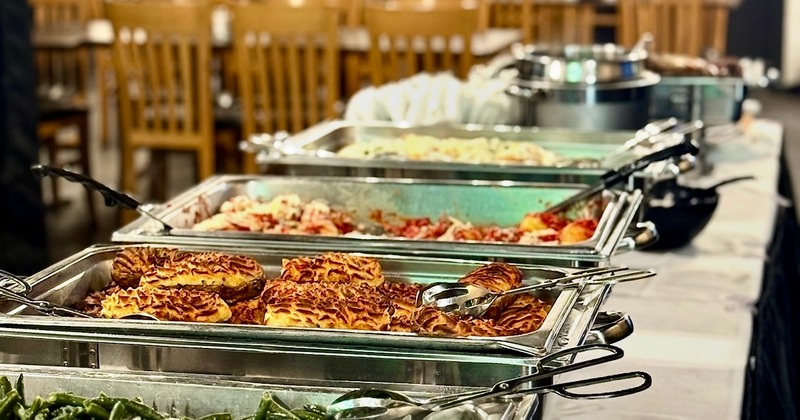 A buffet line with several chafing dishes filled with food