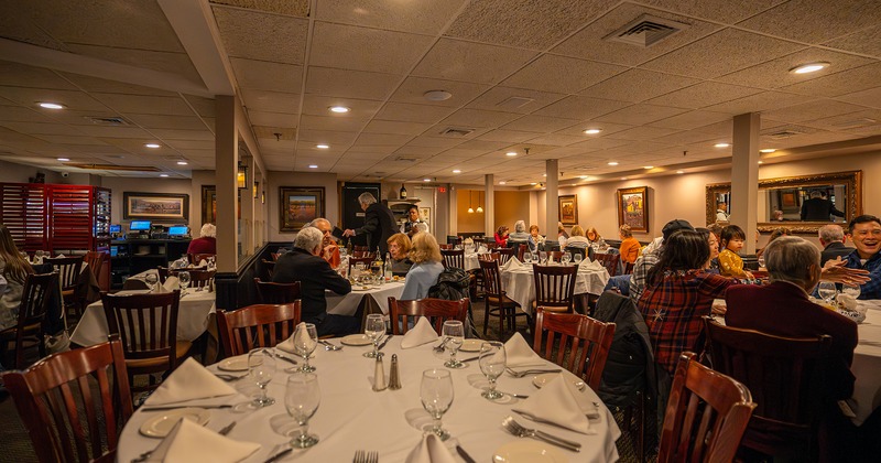 Restaurant interior, dining area with set tables, guests chatting and enjoying their food and drinks