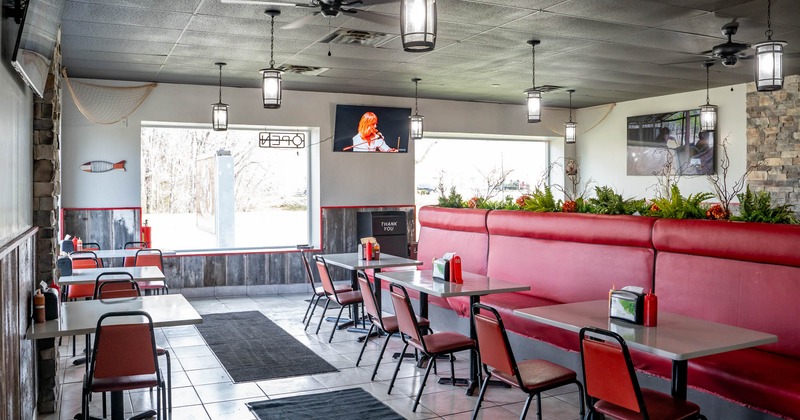 Interior, tables and chairs lined up, red leather seating bench on the right