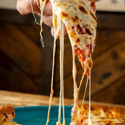 A hand lifting a slice of pizza with melted cheese.