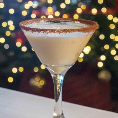 A creamy cocktail in a martini glass, background dotted with soft, glowing lights.