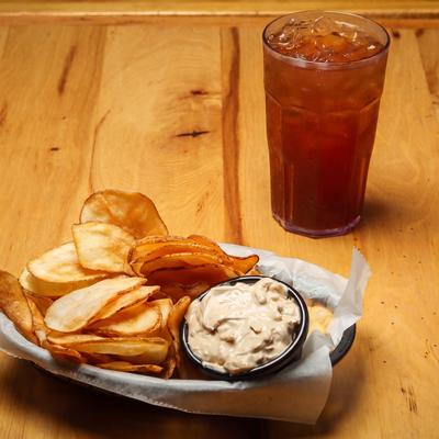 Potato chips served with a side of dip, alongside iced drink.