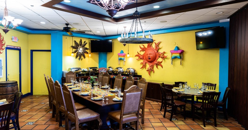 Interior, colorful dining room, long set table, sun sculpture, and buffet station