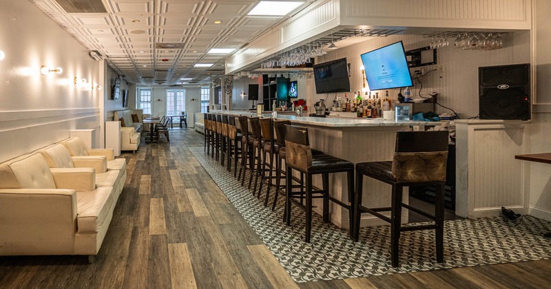 Interior with a bar, wooden bar stools, bright armchairs and a wooden floor