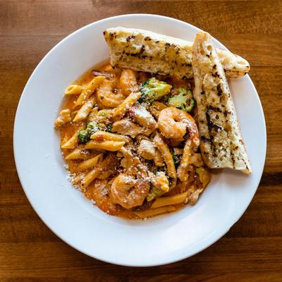 Penne pasta with shrimp, chicken, broccoli, and grilled garlic bread.