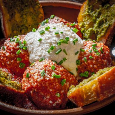 Meatballs topped with cheese beside toasted bread.