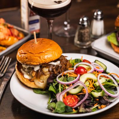 Truffle burger with caramelized onions and cheese, served with a salad and an espresso martini.