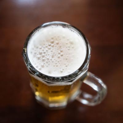 Overhead view of a glass of beer with a frothy head.