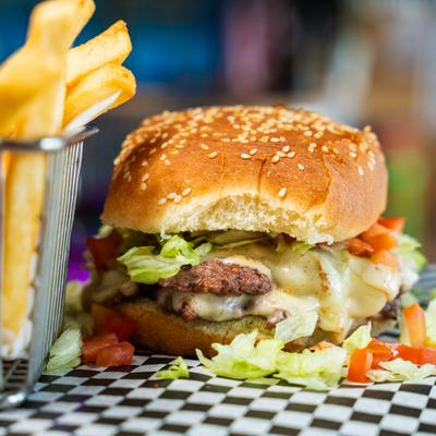 Bacon Cheese Burger with caramelized onions, served with a side of fries.