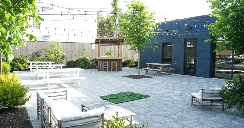 Spacious area on the outside with picnic tables, sofas and lightbulbs as a decoration.