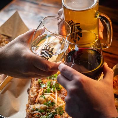 People clinking glasses over table with food.