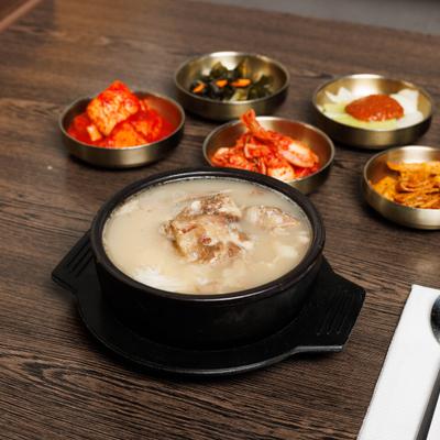 Bowl of Korean milky ox bone soup served alongside various side dishes.