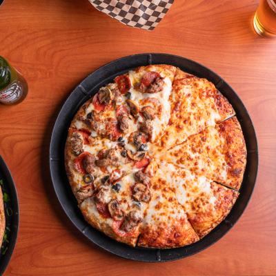 Half and Half pizza served alongside bottle and a glass of beer.