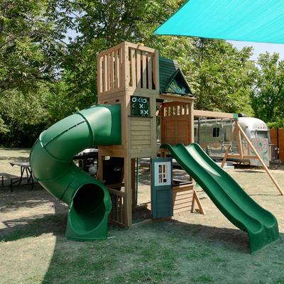 Children’s wooden playground set with green slides.