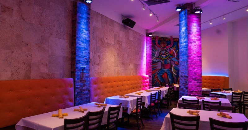 Dining area, high back seating by the walls with tables and chairs, neon lights, mural