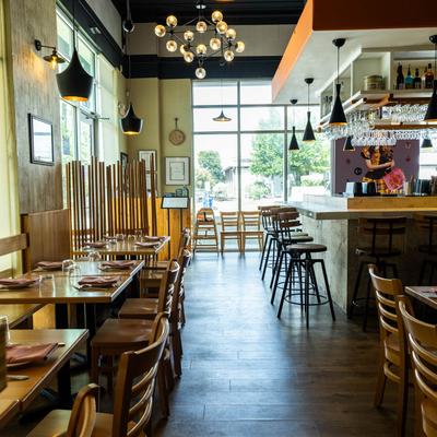 Restaurant interior with a bar, wooden tables, and pendant lighting.