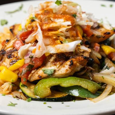 Grilled chicken and peppers topped with cabbage and sauce.