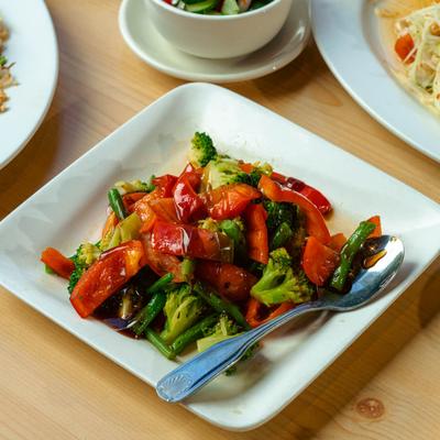 Vegetable stir fry plate surrounded by other dishes.