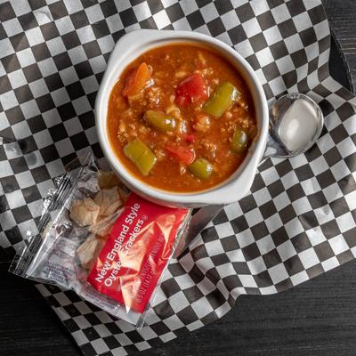Bowl of stuffed green pepper soup served with a side package of crackers.