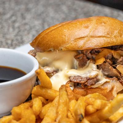 French dip sandwich with melted cheese served with fries and au jus for dipping.
