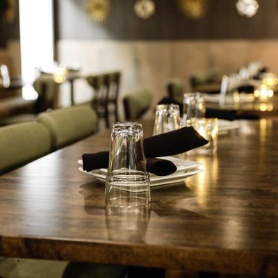 Table set with a clear glass tumbler and a folded black napkin on a small plate.