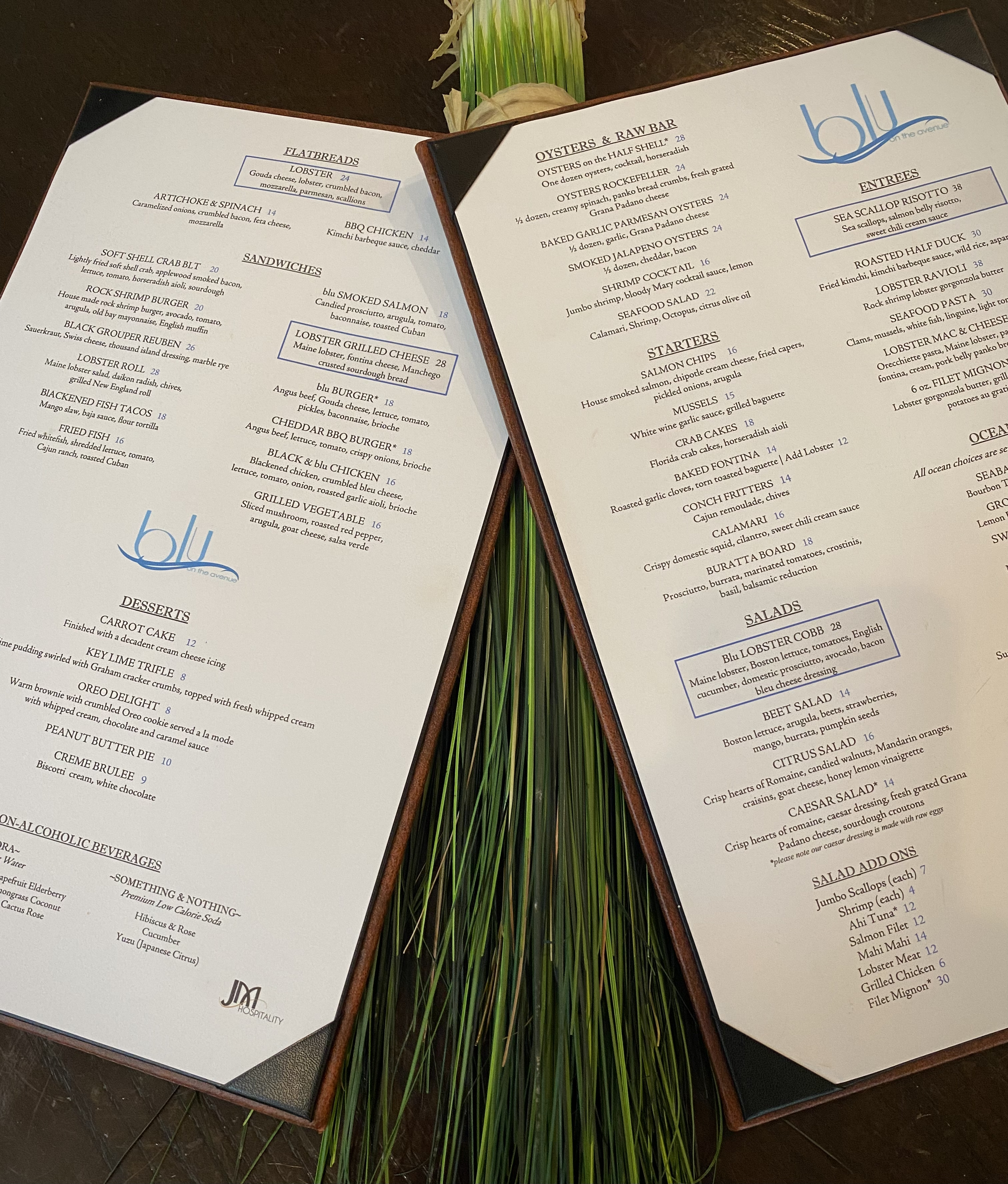 A picture of our new menu on a table with green floral decorations between the pages