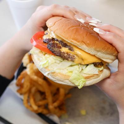 Over the shoulder shot of hands holding double cheese burger