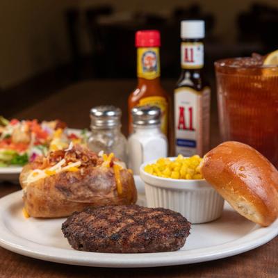 Hamburger steak, corn, baked potato, and a bread roll.