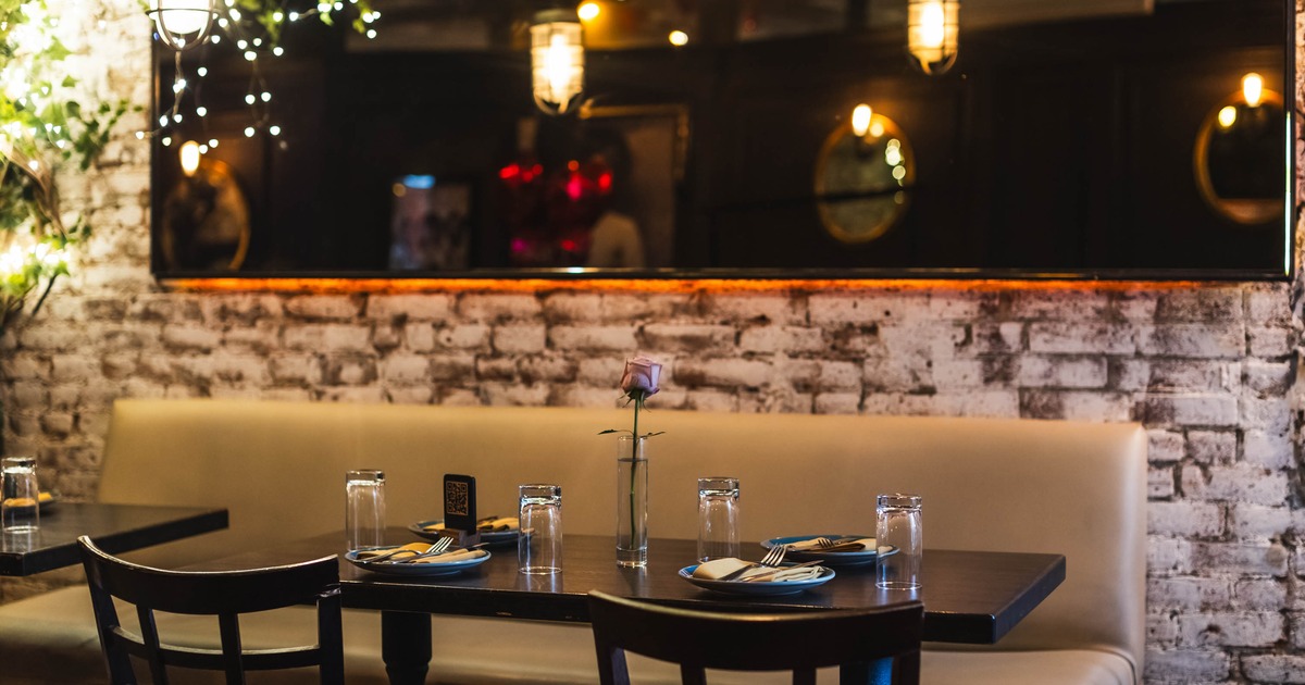 Interior, shared banquette bench with tables for two ad four, large mirror in the back
