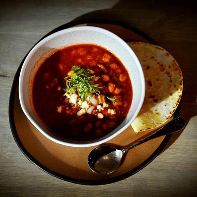 A bowl of pinto beans served with a tortilla.