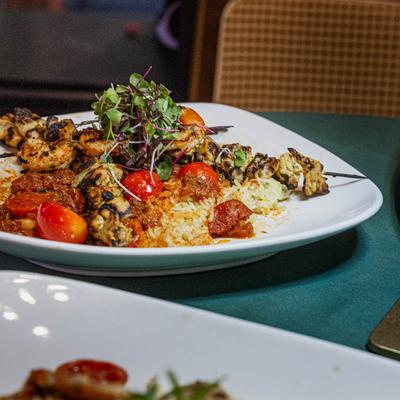 Grilled chicken skewers with rice, tomatoes, and microgreens.