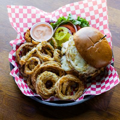 Hangover Burger served with onion rings, salad and a dipping sauce.