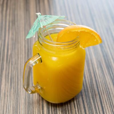 Orange juice glass garnished with umbrella pick and orange wedge