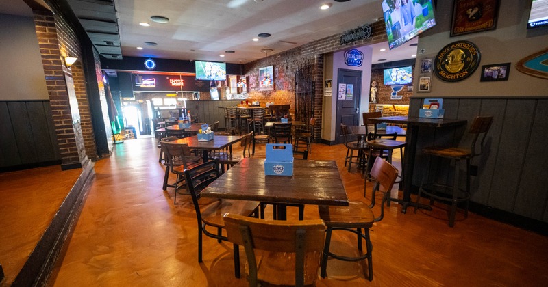 Interior seating area with wooden tables, chairs, brick walls and neon signage
