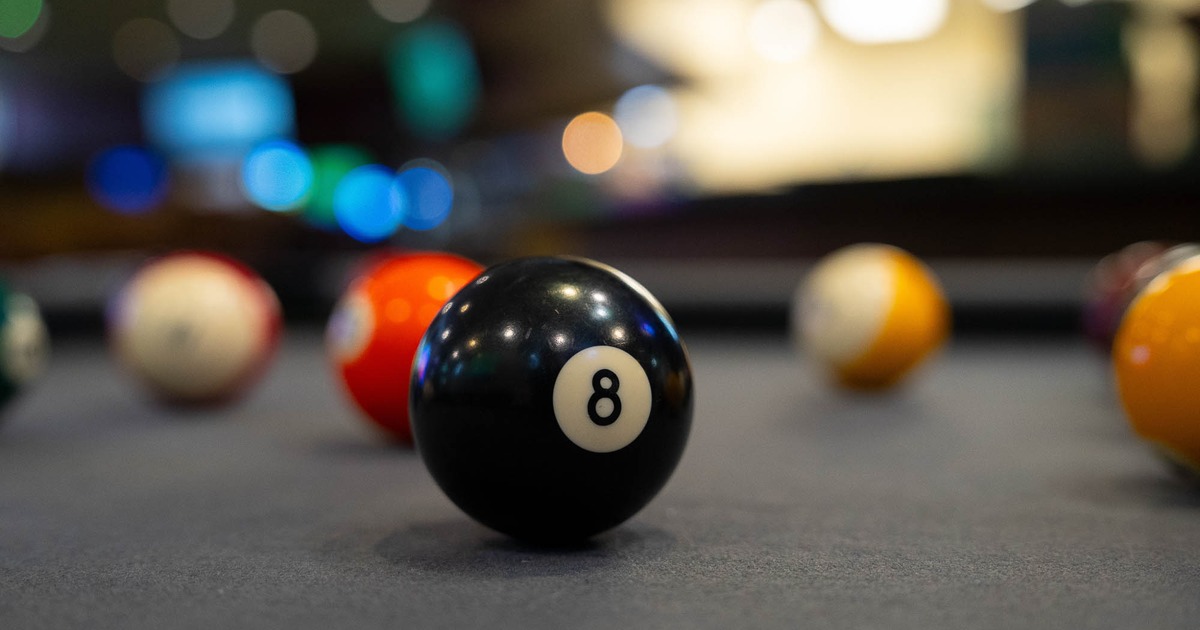 Eight-ball on a pool table surface with other balls in the blurred background
