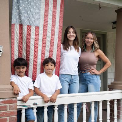 A group standing on a porch with an American flag hanging beside them.