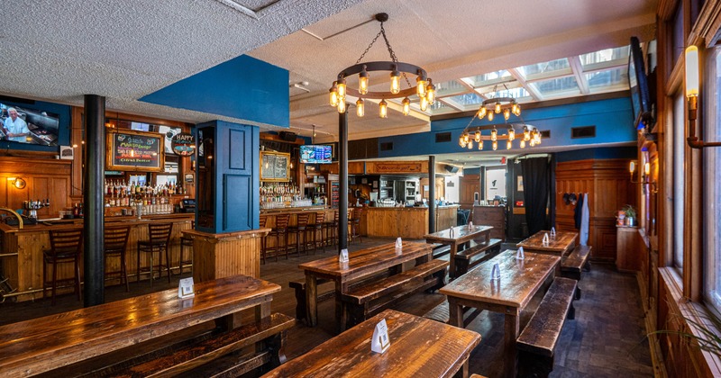 Rustic bar interior, wooden tables, benches, bar counter and ambient lighting from chandeliers