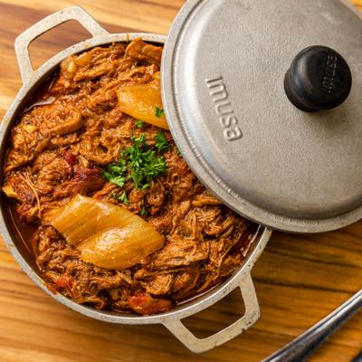 A pot with shredded beef stew in tomato sauce.