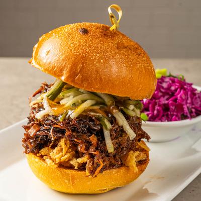 Pulled pork sandwich with Thai peanut sauce, apricot jam, and pickled cucumbers.