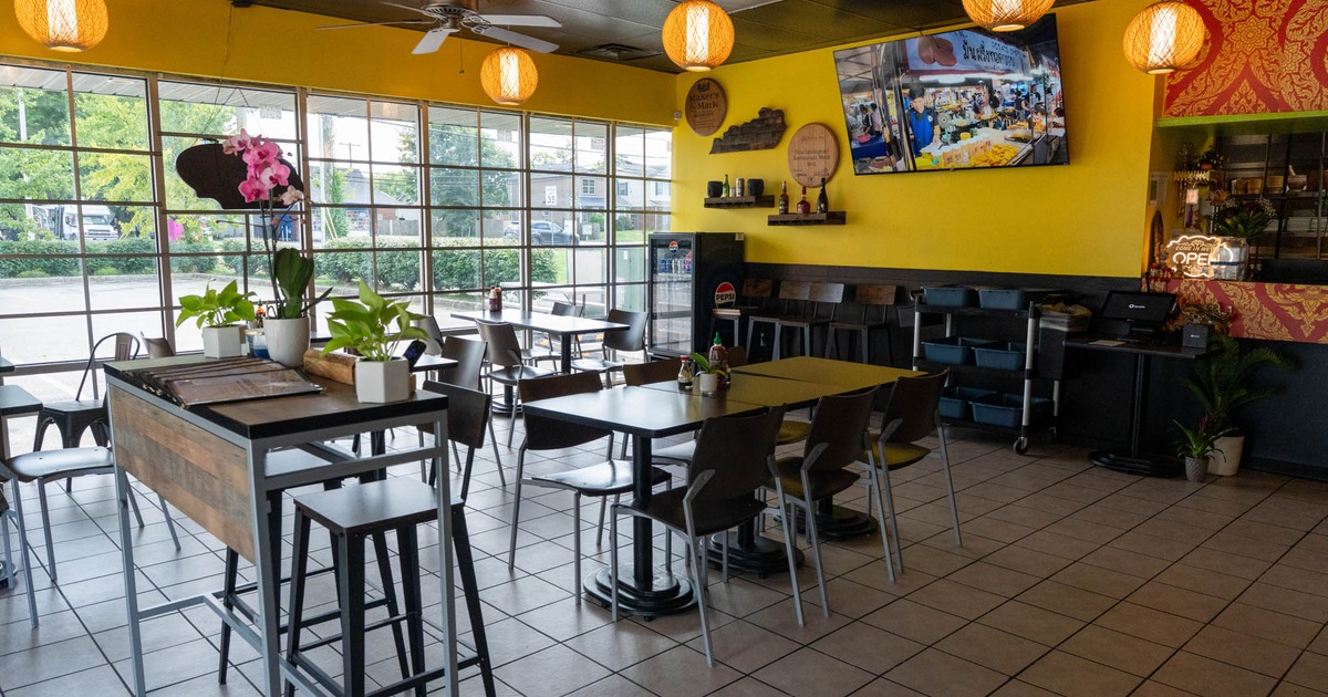 Interior, yellow walls, wooden tables and chairs, hanging wicker lights, and a large window view
